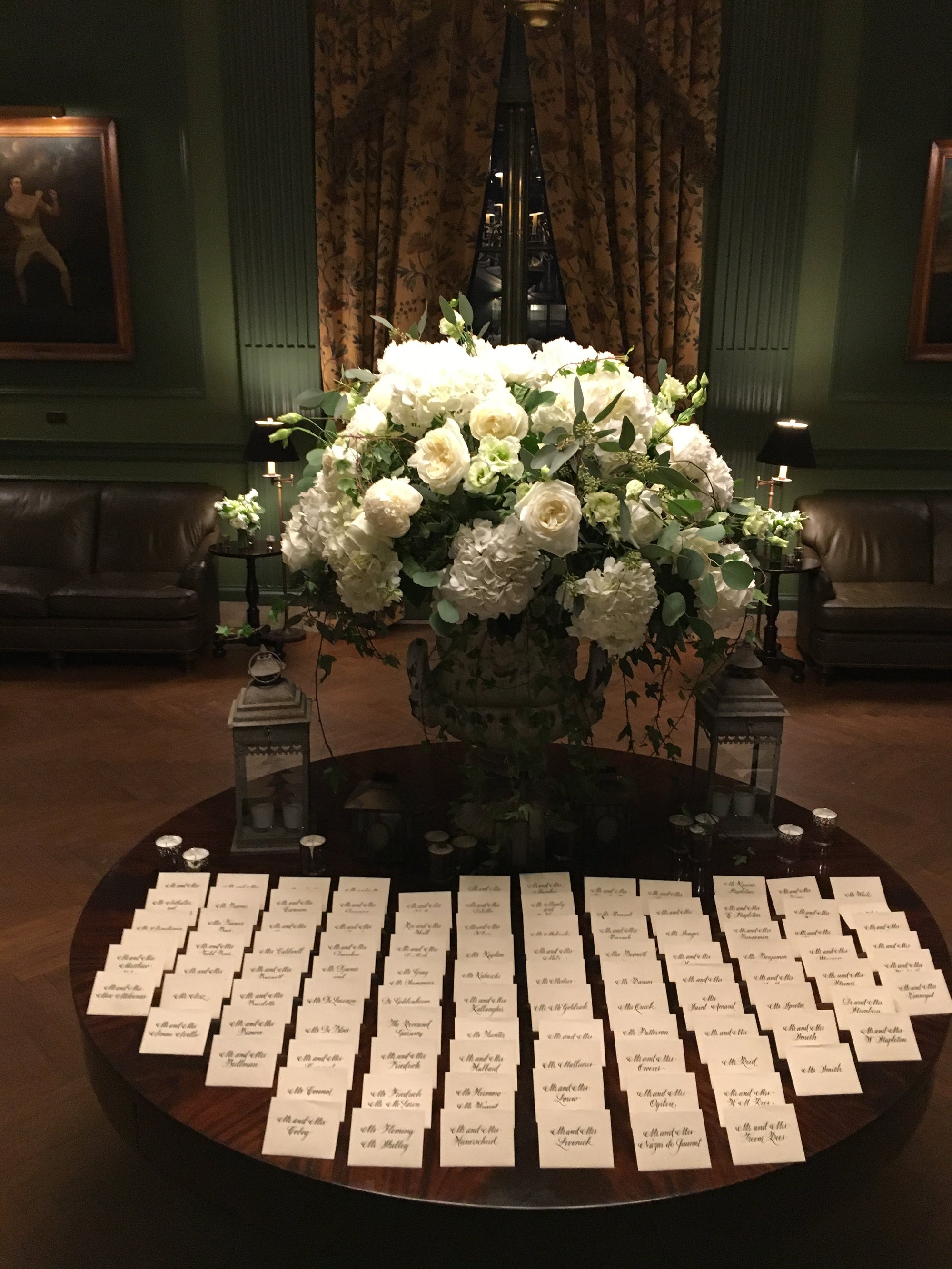 White urn arrangement on an escort card table in a panelled estate room