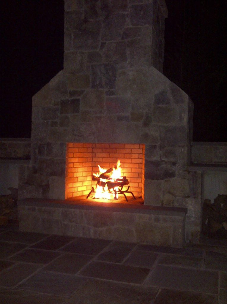 Stone outdoor fireplace glowing at night