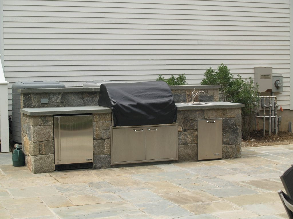 Outdoor kitchen with stainless grill and stone base — representative of entertaining space work