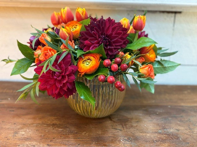 Autumn Sangria — burgundy dahlias, tangerine ranunculus and orange tulips in a fluted champagne bowl